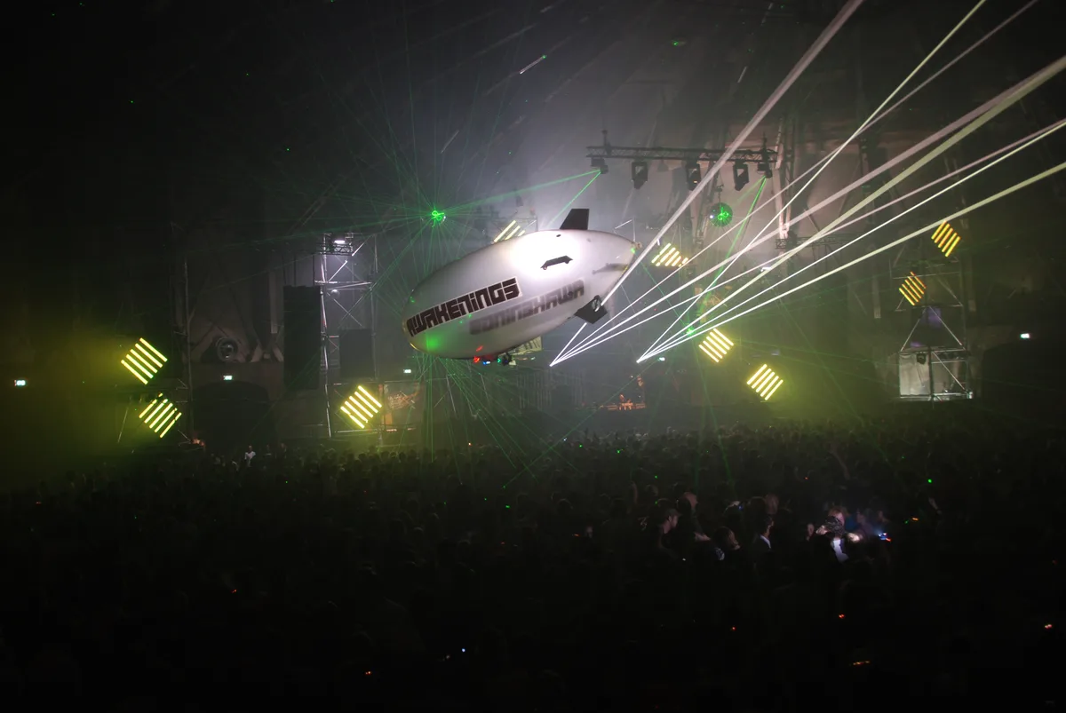 Awakenings' branded airship over the crowd with laser beams crossing the night sky