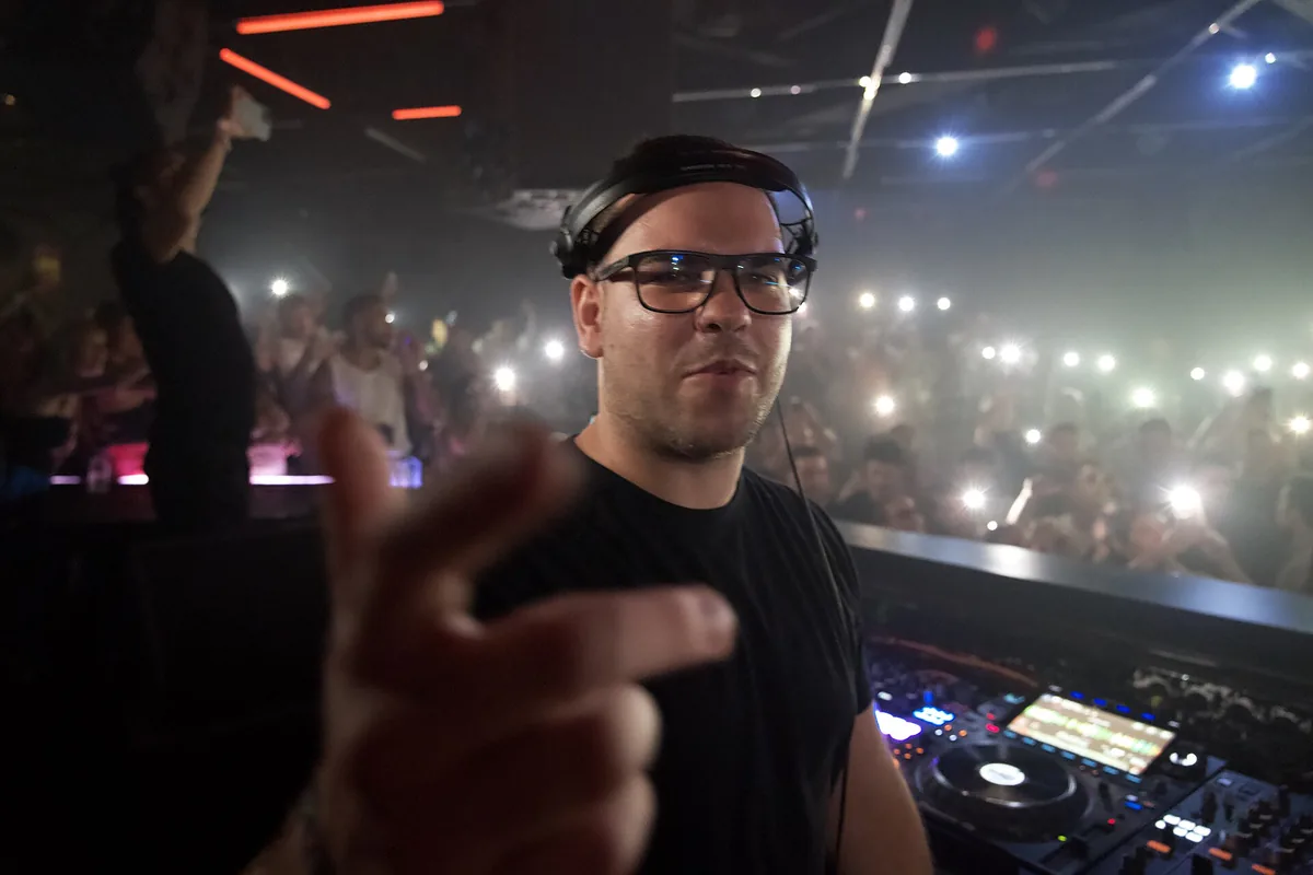 A DJ playing in the Club Room at Hï Ibiza with a crowd holding up phone lights
