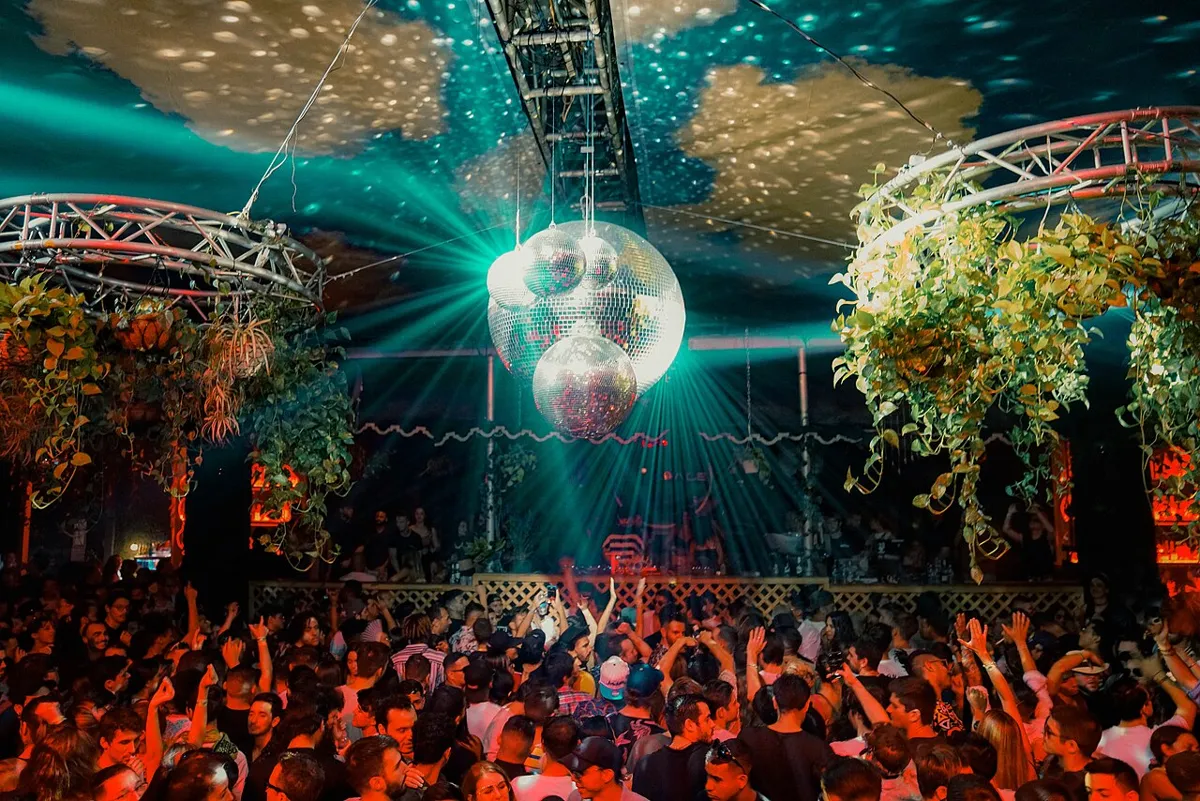 Crowd and mirrorballs under a canopy of plants on the Terrace at Club Space, Miami