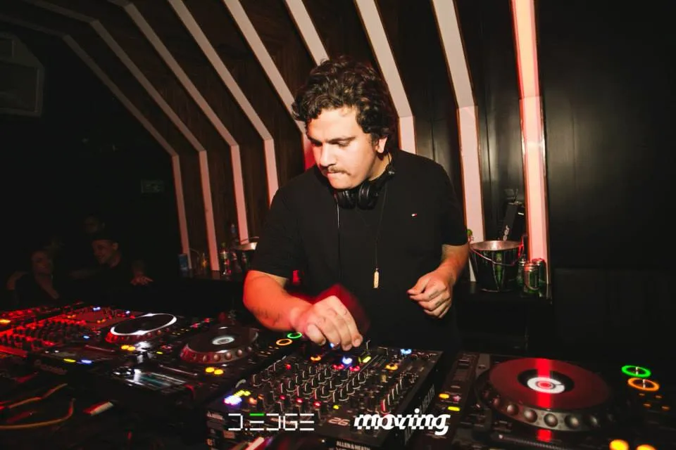 A DJ at the decks at D-Edge in São Paulo, with a banner reading Moving on the mixer