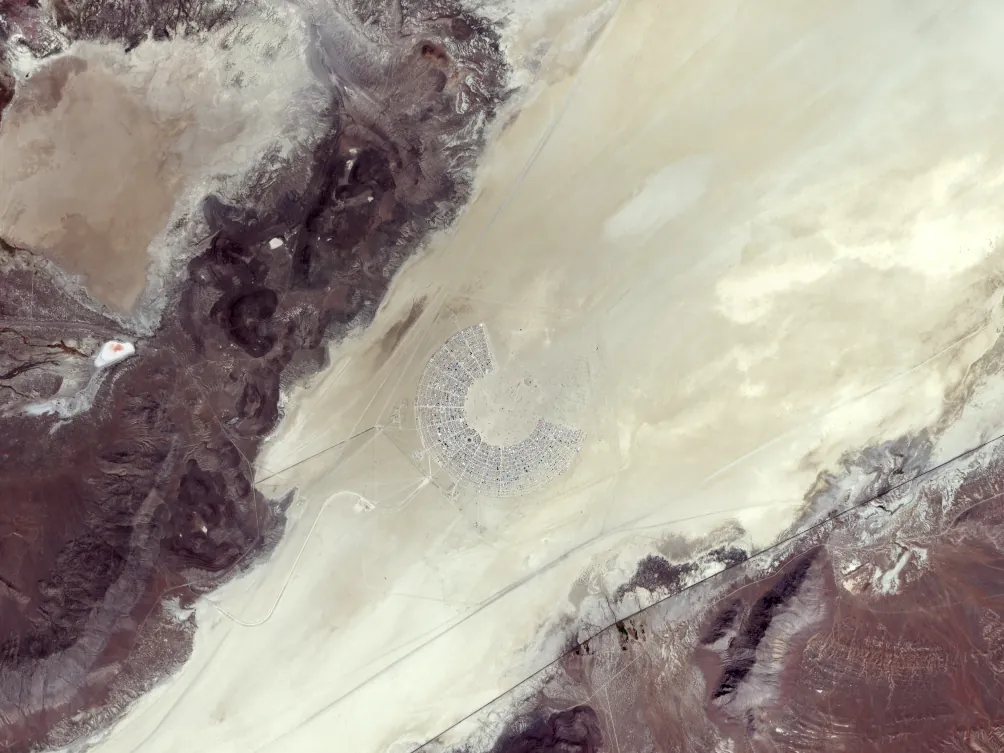 Satellite image of Black Rock City in the Nevada desert, an arc of streets around an open centre