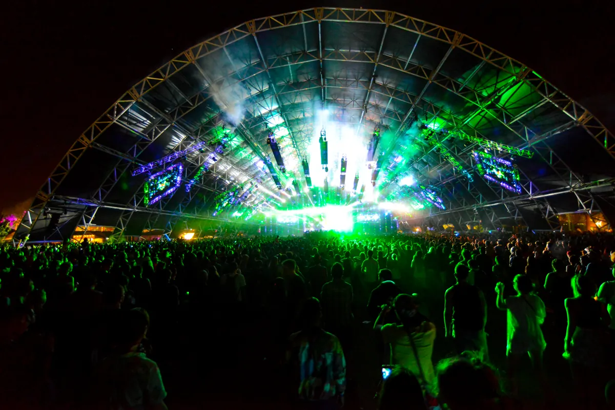 The inside of the Sahara tent at night in 2014, its arched steel frame lit green and white above a packed crowd