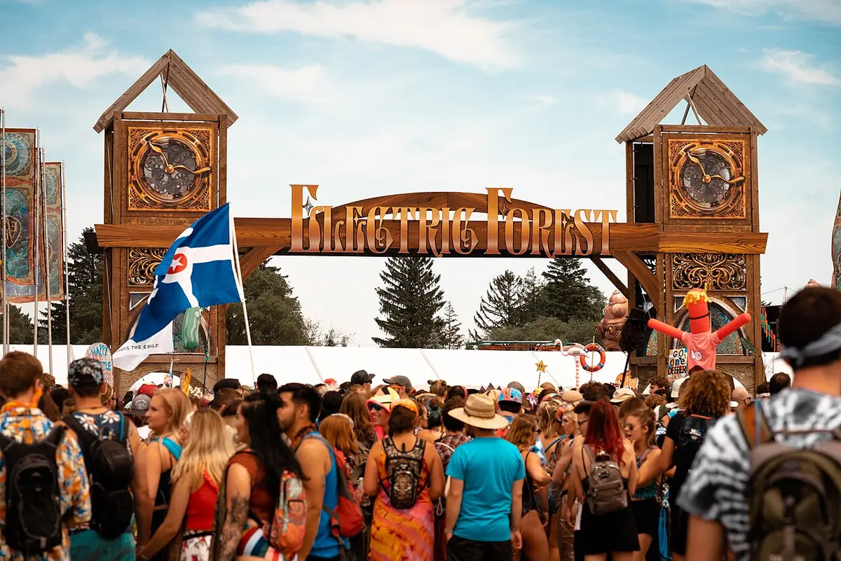 The wooden Electric Forest entrance arch with a crowd of festival-goers in front of it