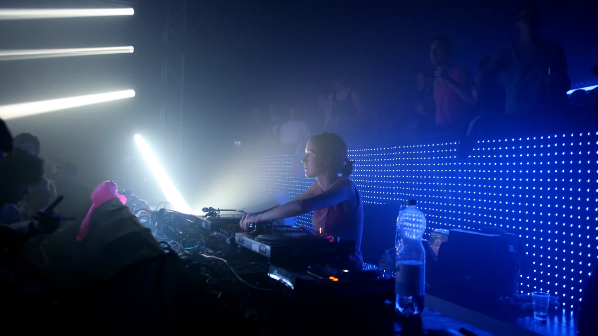 A DJ playing under blue light and strip lights in a dark room at Nachtdigital in 2014