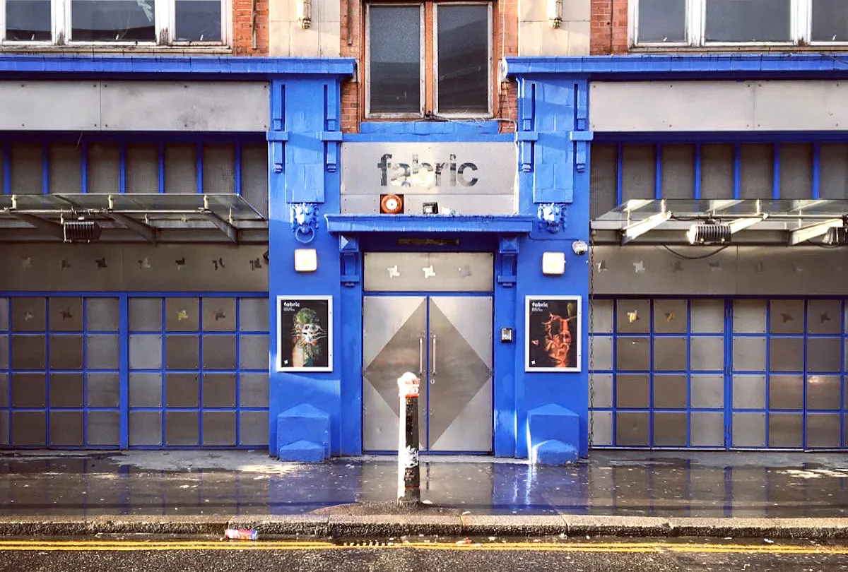 The blue-painted entrance of fabric London with a pair of steel doors and two posters