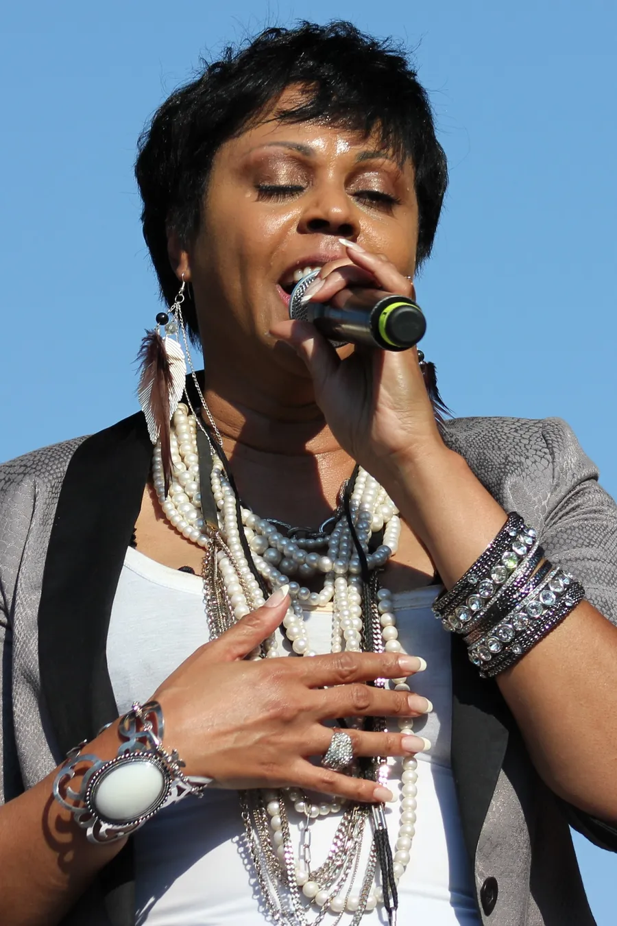 Crystal Waters singing into a microphone on an outdoor stage