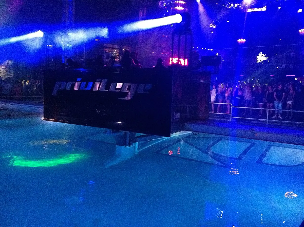 The DJ booth of Privilege Ibiza above the pool in the middle of the dancefloor, lit blue