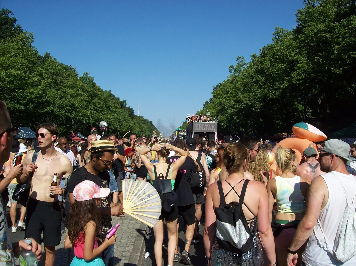A crowd on the Straße des 17. Juni in Berlin at the Rave the Planet parade, with trees and floats in the distance