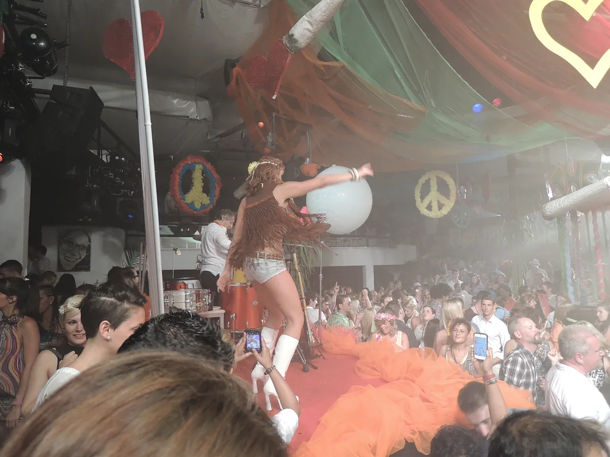 A performer on a stage at a party at Pacha Ibiza, with peace sign decorations behind