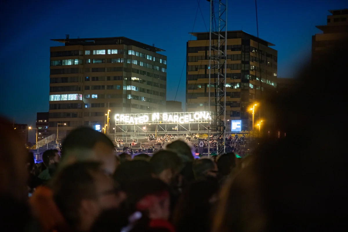 A night crowd at Primavera Sound with a bright sign reading Created in Barcelona above the festival structures
