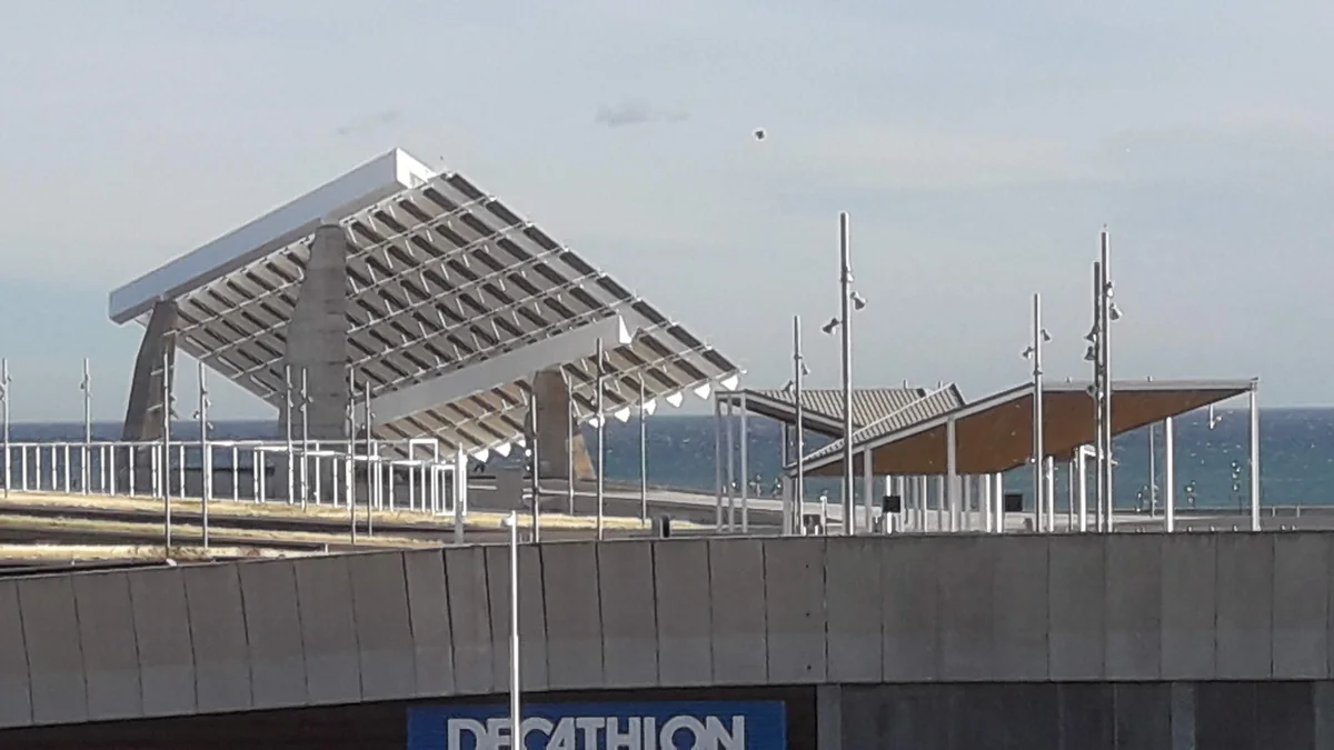 The large photovoltaic canopy and concrete waterfront structures of Parc del Fòrum with the Mediterranean behind