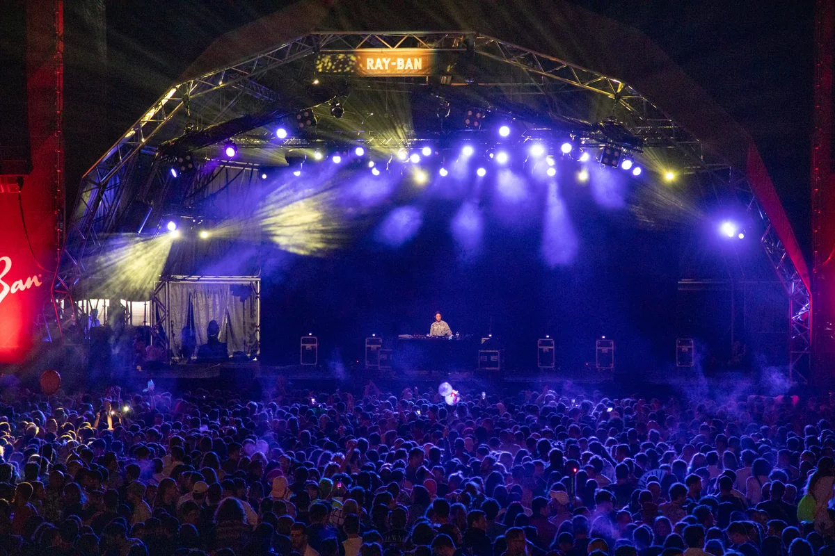 Peggy Gou DJing on the Ray-Ban stage at Primavera Sound 2019 above a dense crowd under purple and yellow lights