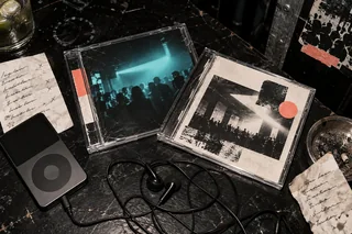 Wired headphones, a portable music player and translucent cases on a scratched club table
