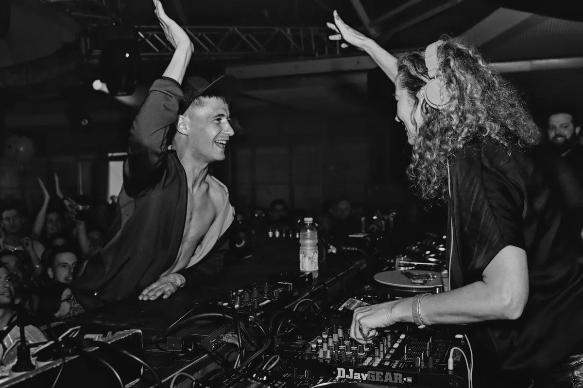 Monika Kruse behind the decks at Time Warp in Mannheim, high-fiving a person in front of the booth